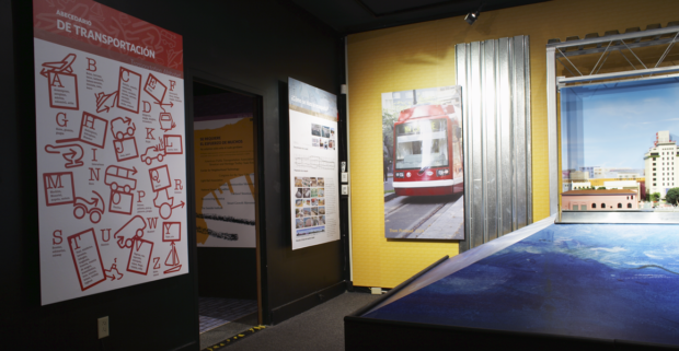 The panel on the left showcases a transportation systems alphabet. The panel in the middle narrates the story of how the HO Scale train model was planned, designed, and built. The panel on the right shows a photo of the Portland Streetcar Tram system. These panels serve as the entrance panels to the community activism section of the exhibit, located through the visible entrance.